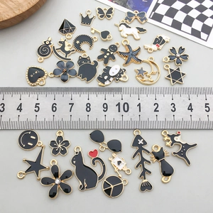 Close-up of assorted black enamel alloy charms including cats and stars on a scale ruler