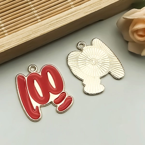 Macro detail of red enamel '100' score charm with gold textured back for DIY jewelry