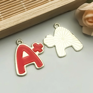 Detailed macro view of gold-plated alloy alphabet A+ pendant with red enamel finish