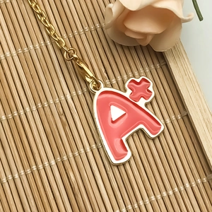 Detail of red enamel letter A pendant with golden chain and lobster clasp on bamboo mat