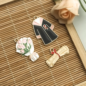 Detail of graduation charms set including gown, tulip bouquet, and diploma scroll