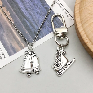Antique silver bell necklace and sled keychain DIY pendant set on a wooden tray