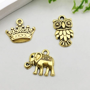 Detail of vintage gold crown, owl, and elephant alloy pendants for DIY jewelry