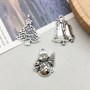 Detailed view of vintage silver Christmas charms featuring a tree, bells, and snowman