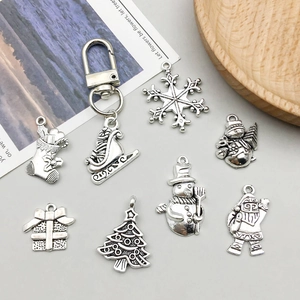 Detail of vintage silver Christmas charms featuring snowflakes, Santa, and bells on a tray