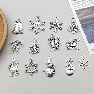 Detailed flat lay of 13 antique silver Christmas charms including snowflakes and bells