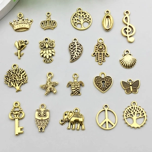 Flat lay view of 20 vintage gold alloy pendants including leaf, crown and butterfly shapes