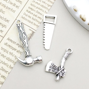 Gros plan de pendentifs outils en alliage argent antique avec marteau, scie et hache