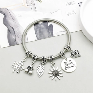 Antique silver bangle with maple leaf, feather, and heart charms, featuring inspirational quote