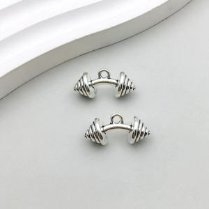 Gros plan de deux pendentifs haltères en argent antique pour création de bijoux