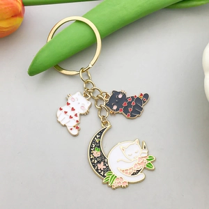 Détails de breloques émaillées dorées avec chat, lune et motifs floraux de clé