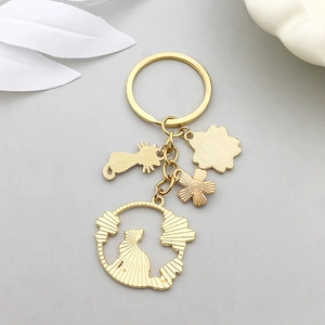Porte-clés doré avec pendentifs chat et fleur sur une texture métallique brossée mate