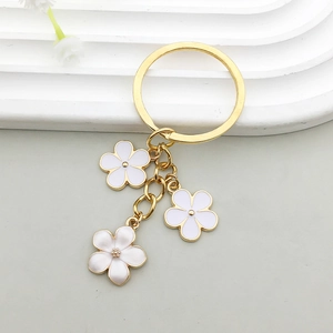 Détail d'un porte-clés fleur blanche avec anneau doré et pétales en émail goutte d'huile