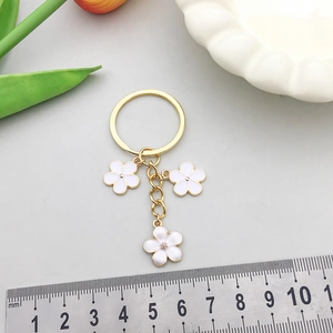 Porte-clés doré avec fleurs en émail blanc et anneau en alliage de zinc