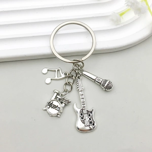 Detail view of antique silver music charms with guitar, drum kit, and microphone