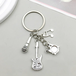 Detailed close-up of antique silver music charms featuring guitar and microphone keychain