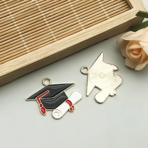 Macro detail of alloy enamel graduation cap and diploma charms for DIY jewelry making