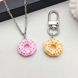 Detailopname van kleurrijke hars donut bedeltjes met roze ketting en gele sleutelhanger