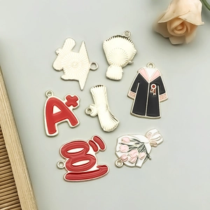 Detailed view of enamel graduation charms with A+ motifs for DIY jewelry design