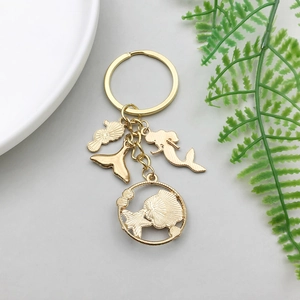 Detailed view of golden mermaid seahorse keychain with oceanic charms on light background