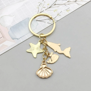 Détail d'un porte-clés doré thème océan avec pendentifs étoile de mer et dauphin