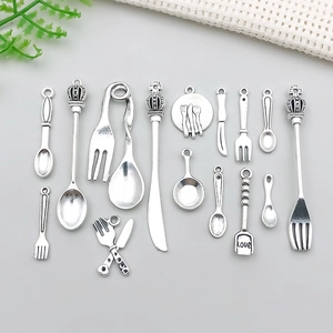 Detailed view of silver alloy cutlery charms with spoon, fork and mini crown pendants