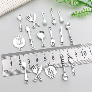 Macro detail of antique silver alloy cutlery charms featuring a spatule with love engraving