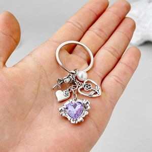 Porte-clés rose en argent vintage avec gemme cœur violette tenu en main pour la taille