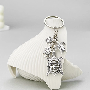 Porte-clés tortue marine argenté avec pendentifs évidés sur support de coquillage