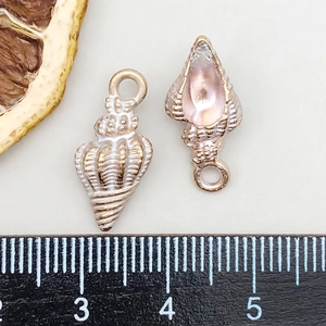 Macro view of shell-shaped alloy pendants with white enamel finish and scale reference