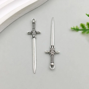 Detailed view of two vintage silver sword pendants with ornate relief hilts for jewelry