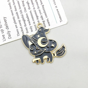 Detail showing a black enamel wizard cat pendant with golden metal outlines on a flat surface