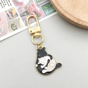 Detail of yin yang cat enamel pendant with a golden lobster clasp on grey background