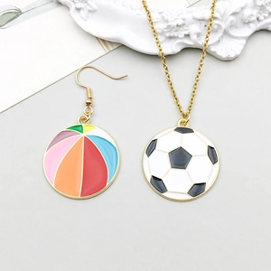 Detail of colorful enamel soccer ball pendant and beach ball earring in gold alloy finish