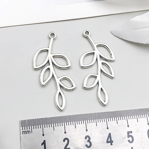 Makroaufnahme von hohlen Blattanhängern aus Silberlegierung mit Maßstab für DIY-Schmuck