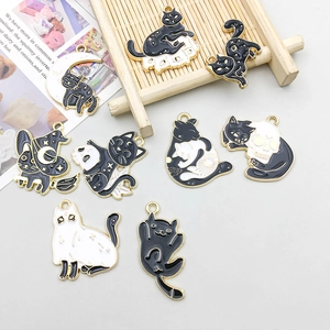 Detail of enamel cat pendants in black and white with gold-plated alloy edges