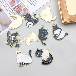 Detail of Halloween cat enamel charms featuring moon and wizard hat motifs on gold backing