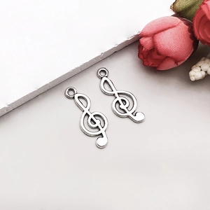 Macro detail of two vintage silver treble clef musical charms for DIY jewelry making