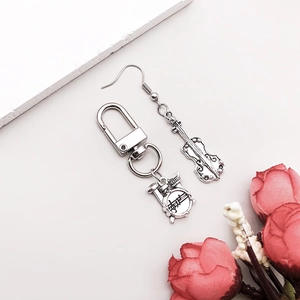 Detail of silver musical instrument charms featuring a cello earring and drum set keychain