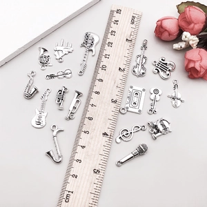Detailed macro view of antique silver music charms with ruler showing tiny dimensions