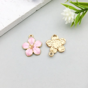Dettaglio di ciondolo a fiore di ciliegio in smalto rosa con retro dorato per gioielli DIY