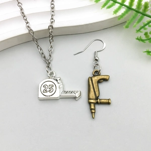 Macro d'un pendentif mètre ruban argenté et boucle d'oreille perceuse en bronze détaillée