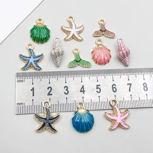 Colgantes de esmalte de concha y estrella de mar con regla para referencia de tamaño