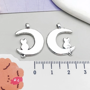 Detail view of silver crescent moon and cat alloy charms with ruler showing 1.8cm width
