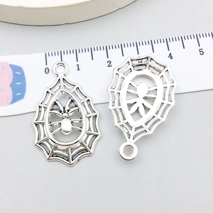 Detail view of silver spider web pendants with scale ruler showing 3cm size for DIY jewelry