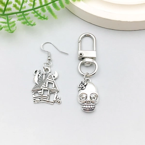 Detailed view of antique silver haunted house earring and floral skull pendant charm