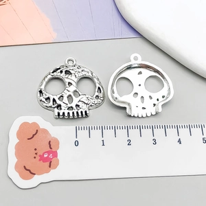 Macro detail of antique silver skull pendants with ruler showing 25mm width dimension