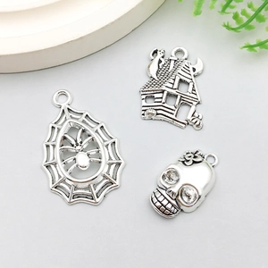 Detailed antique silver charms including a spider web, haunted house, and skull motifs