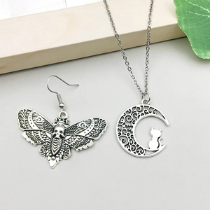 Detalle de colgantes de plata antigua con motivos de polilla y gato en la luna