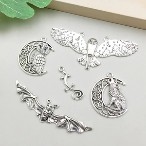 Detalle de dijes de plata antigua con murciélagos, búhos y lobos para joyería artesanal